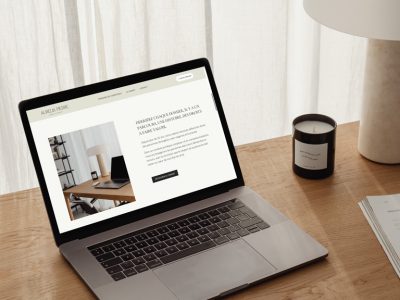 Vue du site Squarespace du Cabinet d'avocat sur un ordinateur portable, posé sur un bureau en bois avec une lampe et une bougie.